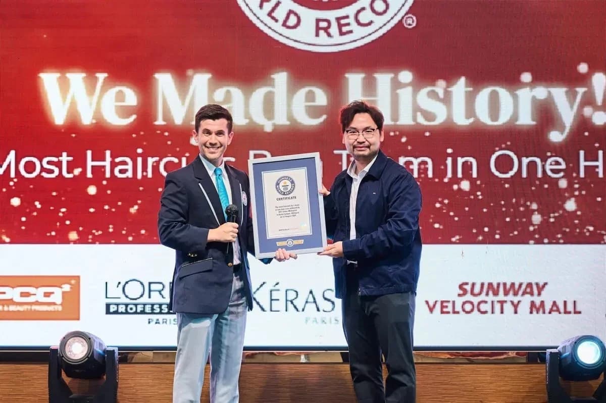 Two people holding a framed certificate on stage at the APT event.