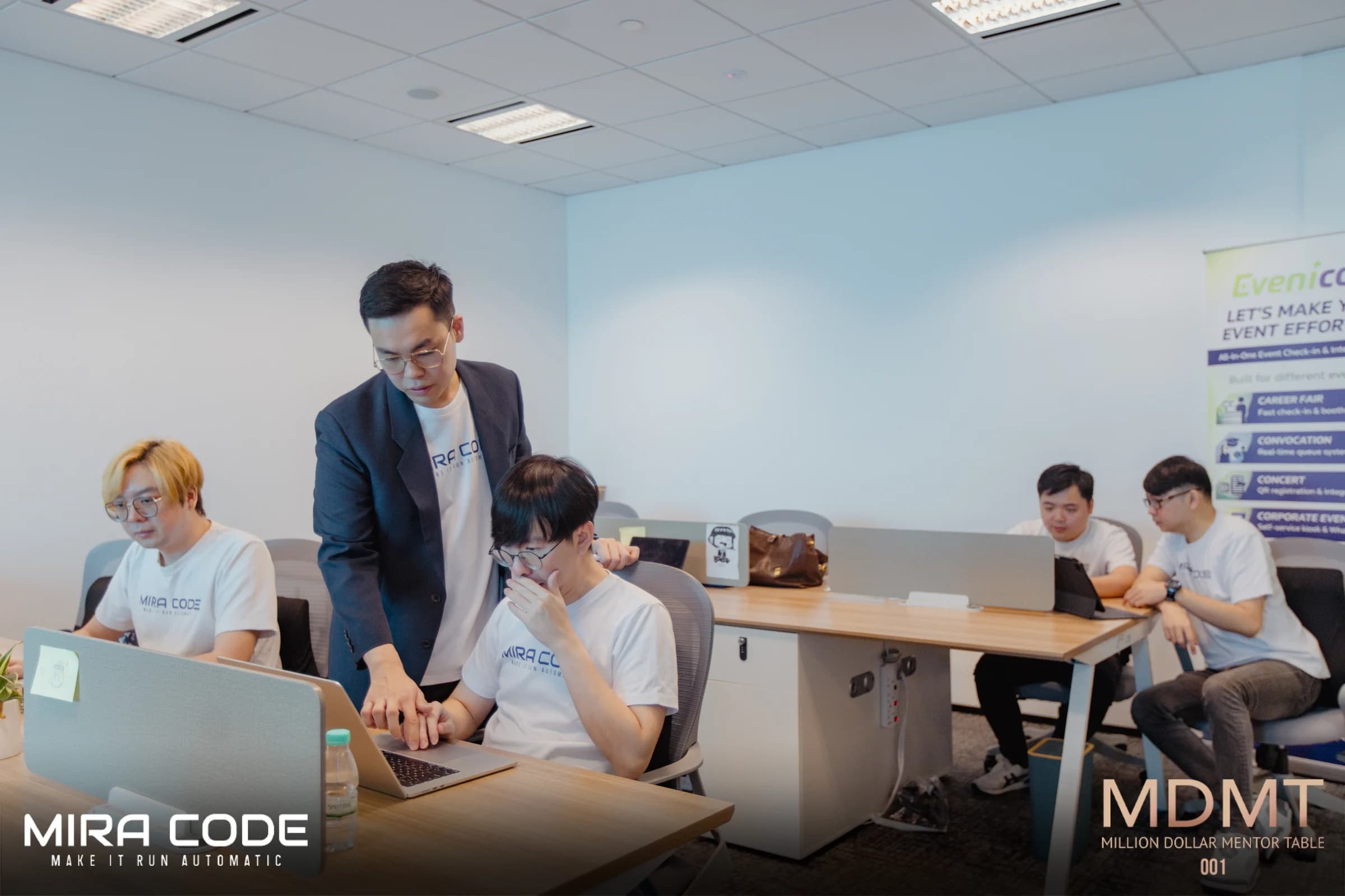 MIRA CODE teammates reviewing software together at their office desks.