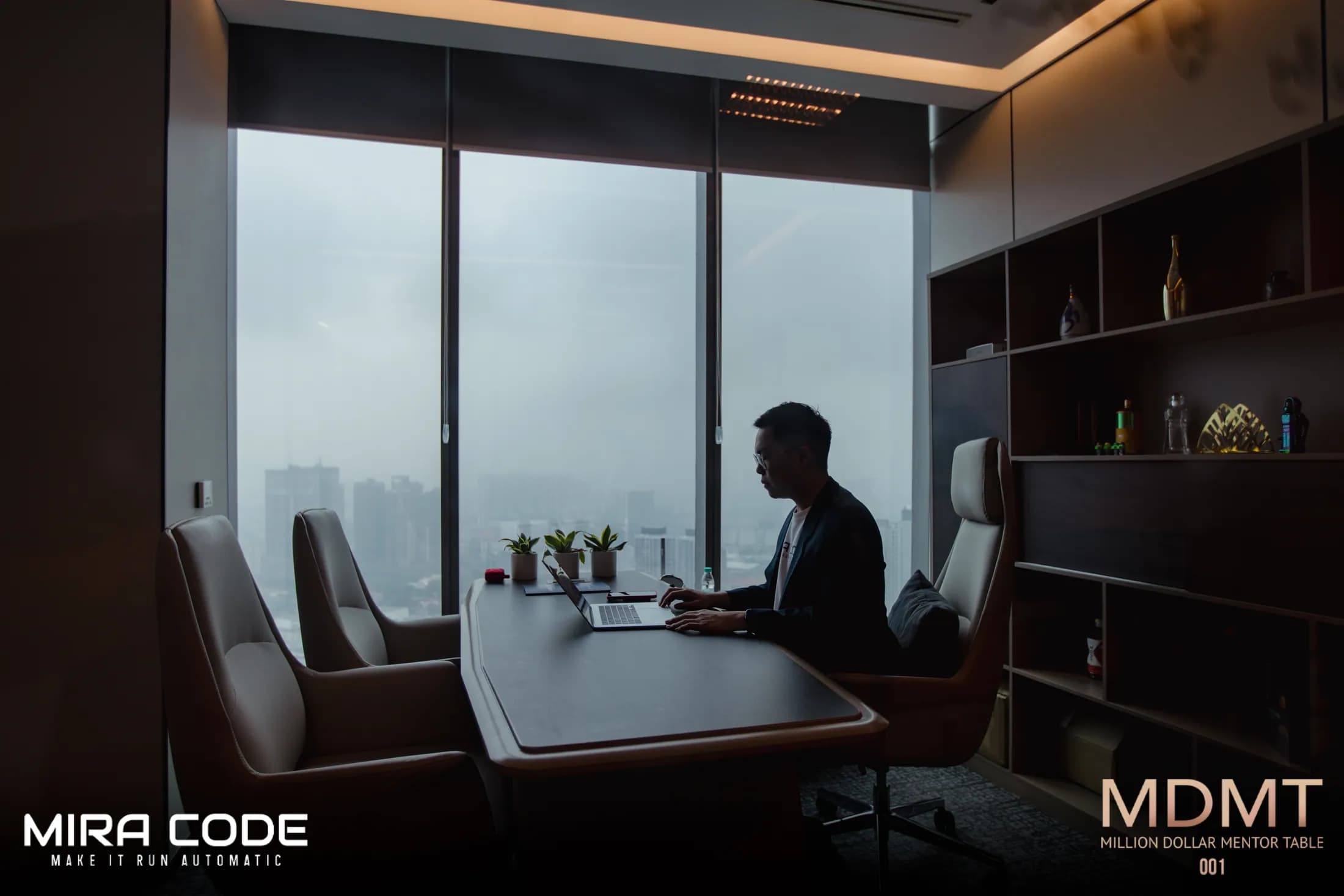 A MIRA CODE team member working on a laptop in a meeting room.